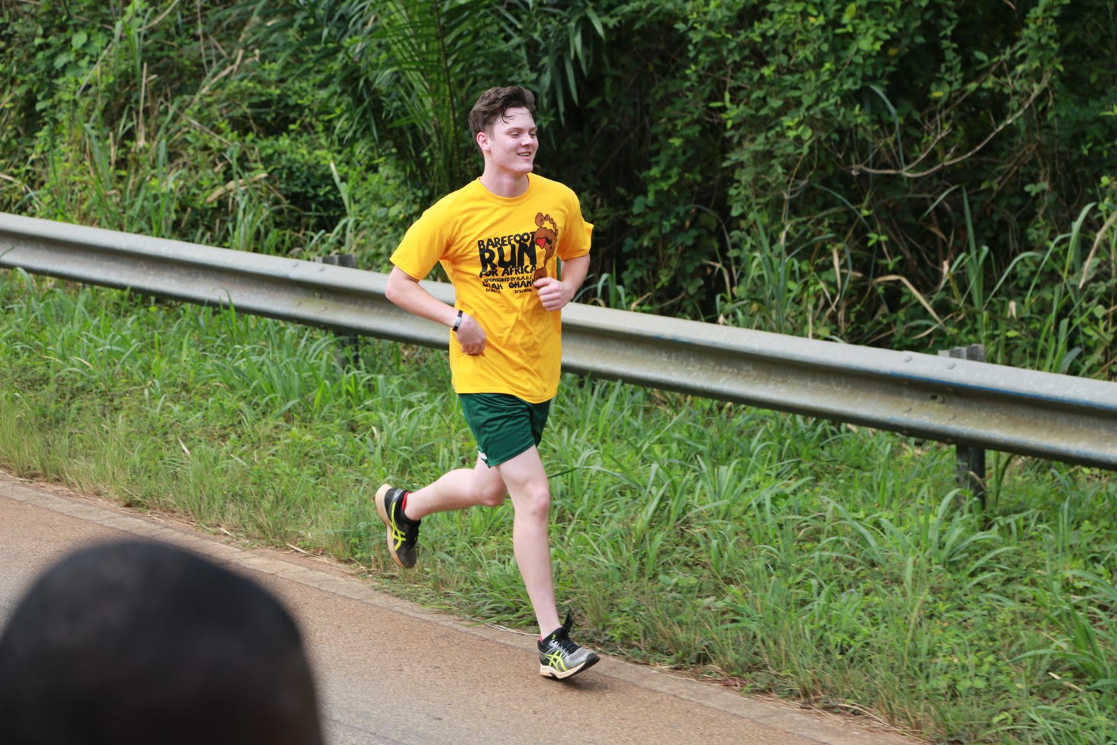 A volunteer in the race shirt running along the guardrail