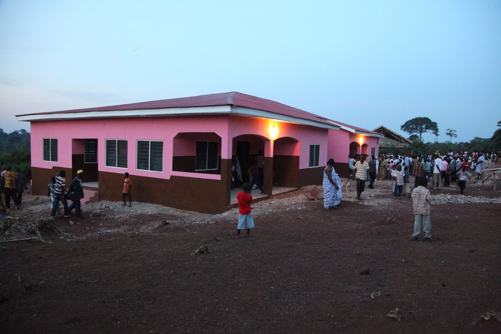 A newly built clinic at dusk with neighbors gathered outside