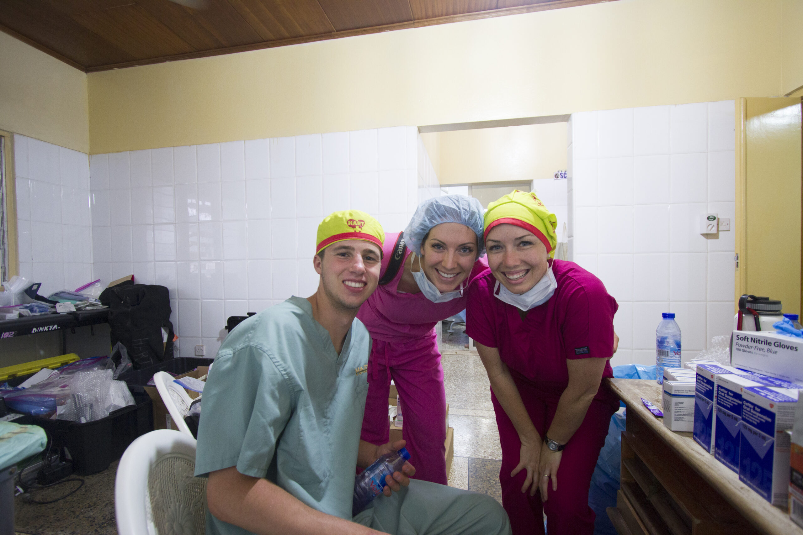 HART volunteers in scrubs smiling in the supply room between cases